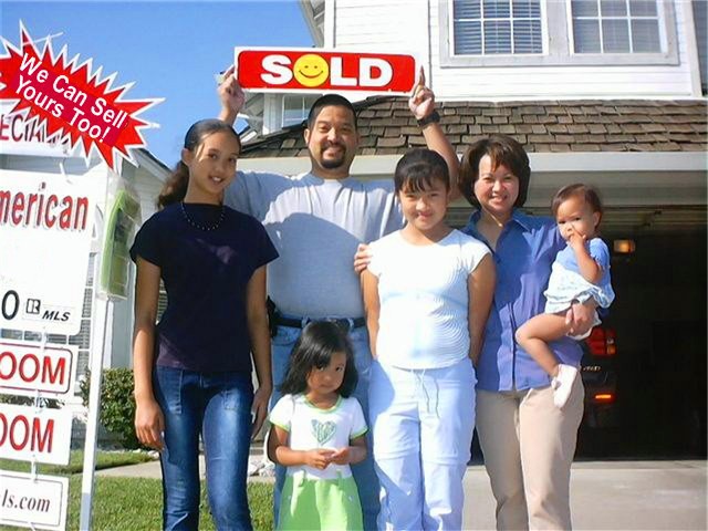 Photo of our clients with their SOLD sign in their front yard with garage door open.